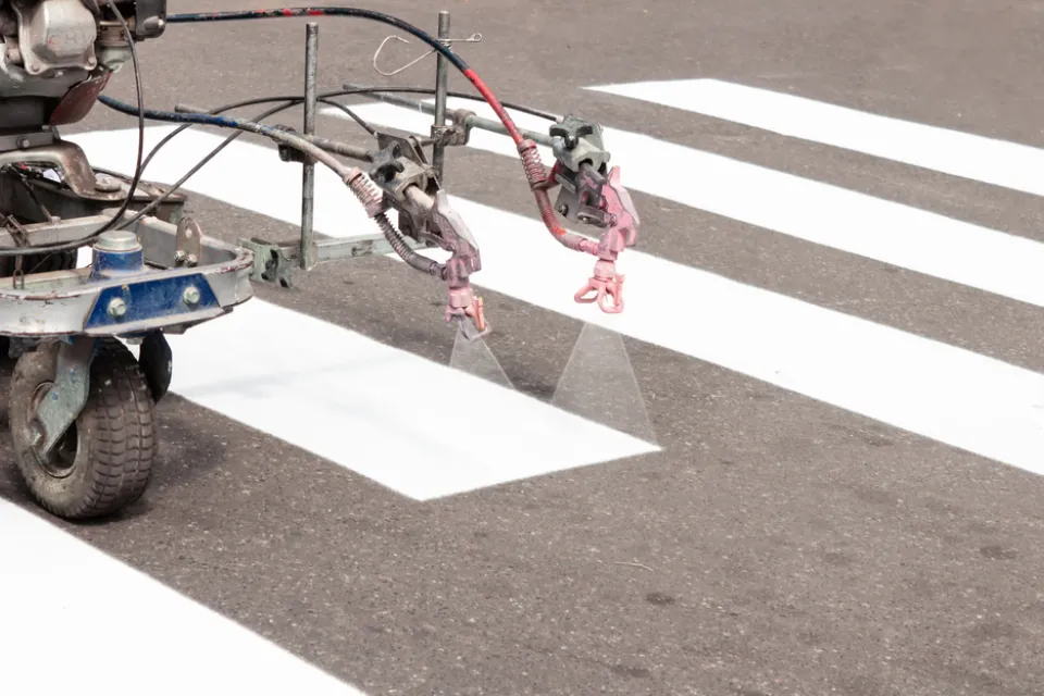 Machine spraying white crosswalk lines on street